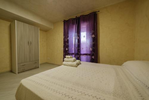 a bedroom with a large white bed with purple curtains at Tenuta del Bifan in Policastro Bussentino