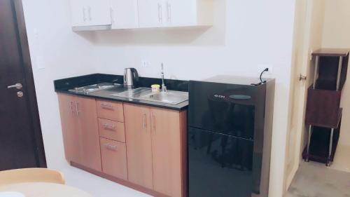a kitchen with a sink and a black refrigerator at Palm Tree Villas 1 in Manila