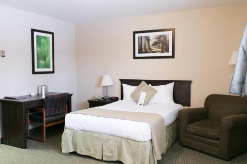 a hotel room with a bed and a chair at Victoria Inn Flin Flon in Flin Flon