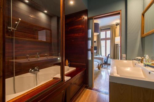 een badkamer met een bad, een wastafel en een spiegel bij Cornerhouse Level Ten by Romy&Travis in Brugge