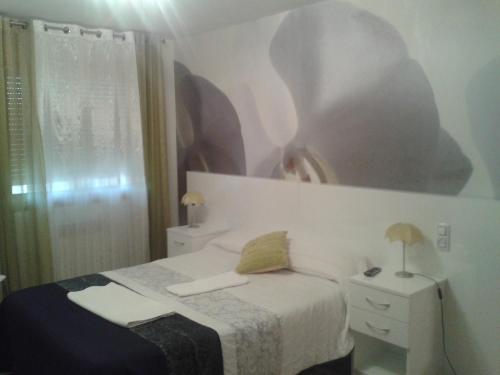 Hostal Texas 2 في Fuentes de Ebro: غرفة نوم بسرير ودهان على الحائط