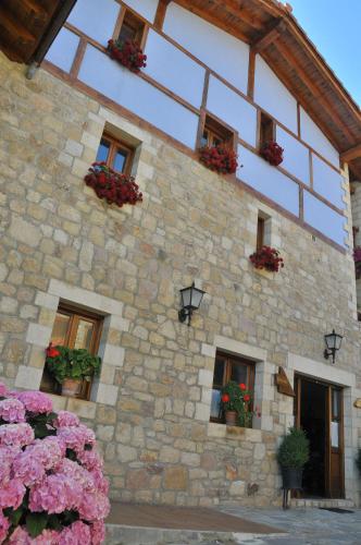 a stone building with flowers in front of it at Viviendas Rurales Peña Sagra in Cahecho