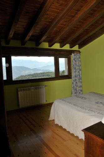 a bedroom with a bed and a large window at Viviendas Rurales Peña Sagra in Cahecho