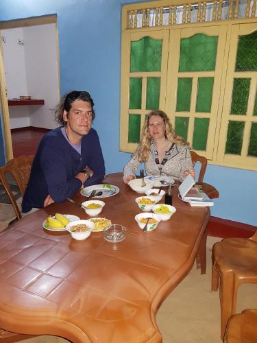 a man and a woman sitting at a table with food at Nilaveli Beach Rooms in Nilaveli