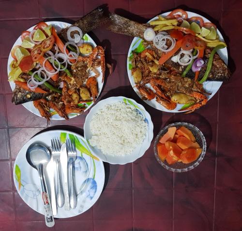 a table topped with plates of food and bowls of rice at Nilaveli Beach Rooms in Nilaveli