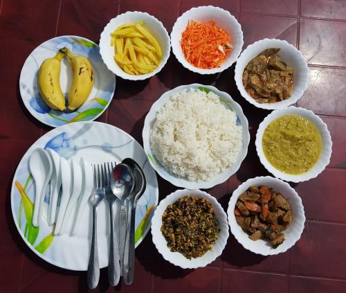 a table topped with plates and bowls of food at Nilaveli Beach Rooms in Nilaveli