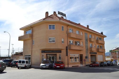 un gran edificio de ladrillo con coches aparcados en un aparcamiento en Hostal Lady Ana María en Collado-Villalba