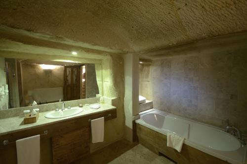 a bathroom with a tub and a sink and a mirror at Fresco Cave Suites Cappadocia in Urgup