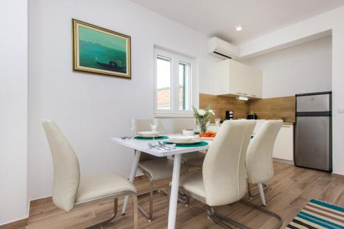 a kitchen and dining room with a white table and chairs at Riva in Krapanj
