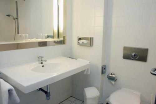 a white bathroom with a sink and a toilet at Stadthotel Oranienburg in Oranienburg