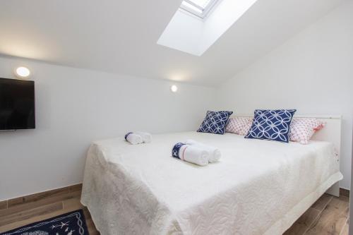 a bedroom with a white bed with pillows and a tv at Riva in Krapanj
