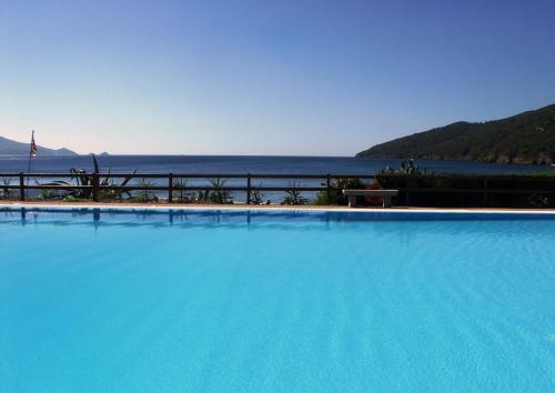 a large blue swimming pool with a view of the ocean at Hotel Capo Sud in Lacona