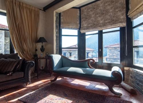 a living room with a blue couch in front of windows at Ostra Menalon Luxury Suites in Kardharás