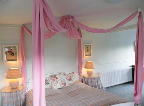 a bedroom with a canopy bed with pink curtains at Das Bärenhaus in Bergen