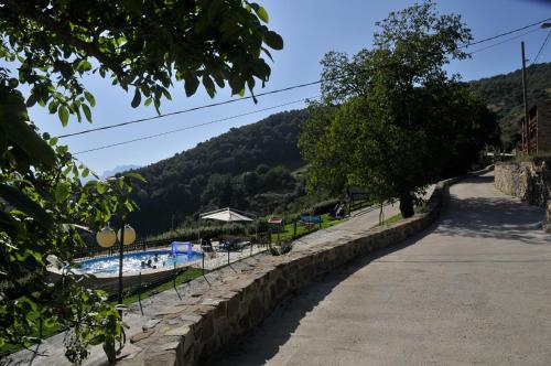 a road next to a swimming pool and a mountain at Viviendas Rurales Peña Sagra in Cahecho