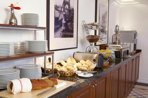 a kitchen with a counter with plates and bread at Mirage Medic Hotel in Budapest