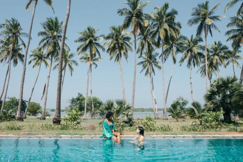 two children playing in a swimming pool in front of palm trees at Luna Laguna in Kalpitiya
