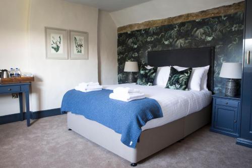 a bedroom with a large bed with a blue blanket at Wynnstay Arms, Ruabon, Wrexham in Ruabon