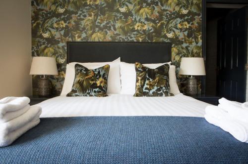 a bedroom with a bed with pillows and a floral wallpaper at Wynnstay Arms, Ruabon, Wrexham in Ruabon