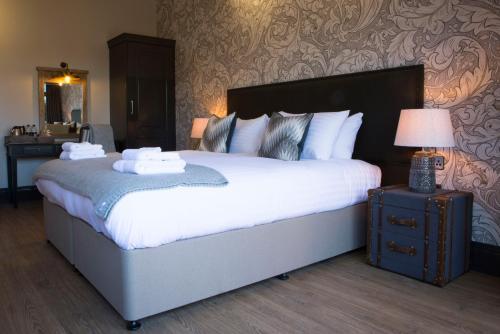 a bedroom with a large bed and a lamp on a table at Wynnstay Arms, Ruabon, Wrexham in Ruabon