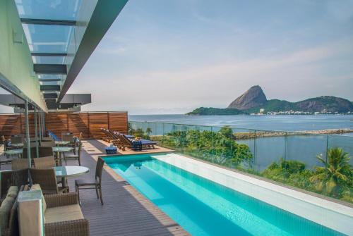 uma piscina com cadeiras e vista para o oceano em Prodigy Santos Dumont no Rio de Janeiro