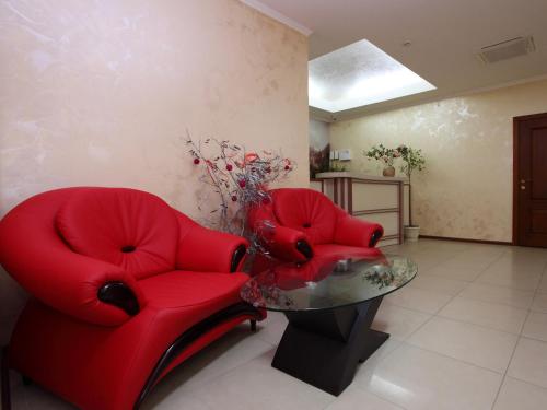 a living room with two red chairs and a table at Paradise Hotel in Svitlovodsʼk