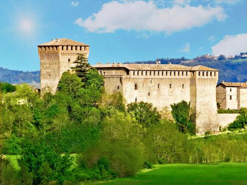 un grande castello su una collina con un campo verde di Albergo Della Roccia a Varano deʼ Melegari