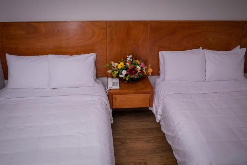 a hotel room with two beds and a table with flowers at AMD Hotel in San Juan de los Lagos