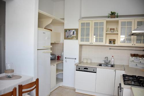 a white kitchen with a sink and a refrigerator at Ammos Apartments in Ierápetra