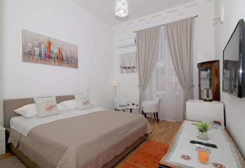 a white bedroom with a bed and a table at Dreams Stradun Apartments in Dubrovnik