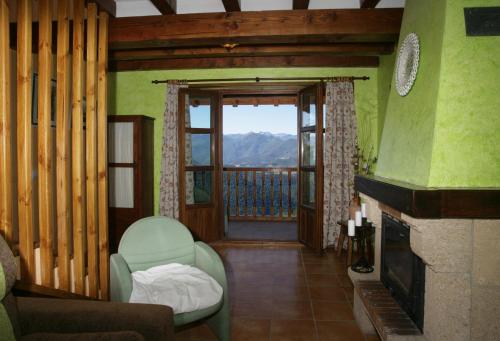 a living room with a fireplace and a door to a balcony at Viviendas Rurales Peña Sagra in Cahecho