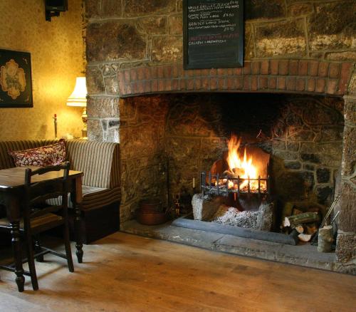 a stone fireplace in a room with a table and a table at The Globe Inn in Chagford