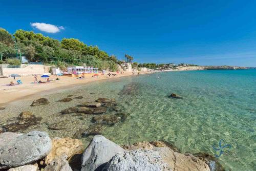 a beach with people in the water and rocks at B&B AMURI RANNI in Avola