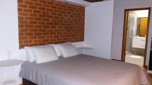 1 dormitorio con 1 cama con pared de ladrillo en Rio NaturAL, en Vila Nova de Milfontes