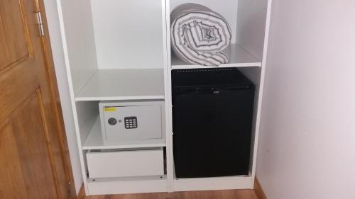 a small white cabinet with a microwave and a refrigerator at Rio NaturAL in Vila Nova de Milfontes