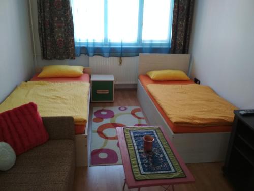 um pequeno quarto com 2 camas e um sofá em Apartman Lux em Szeged