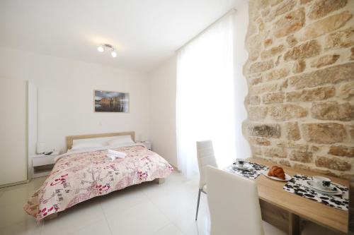 a bedroom with a bed and a stone wall at Sites of Zadar Apartments in Zadar