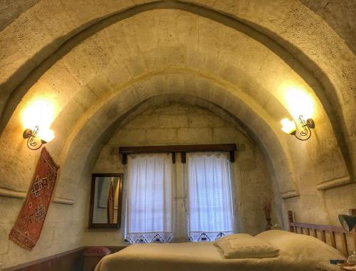 a bedroom with an archway with a bed and a window at Aravan Evi in Ürgüp