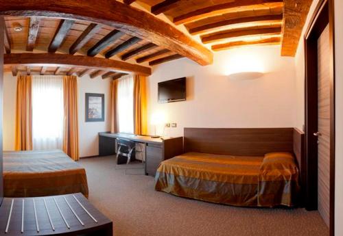 a hotel room with two beds and a desk at Locanda Sant'Ambrogio in Rivalta