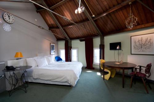 een slaapkamer met een bed en een tafel en een klok bij Villa Augustus in Dordrecht