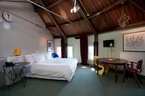 a bedroom with a bed and a table and a clock at Villa Augustus in Dordrecht