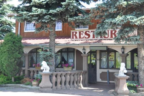 a restaurant with statues in front of a building at Zajazd pod Lwem in Trzebnica