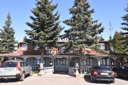 two cars parked in a parking lot in front of a restaurant at Zajazd pod Lwem in Trzebnica