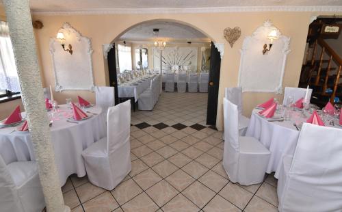 a banquet hall with white tables and chairs with red napkins at Zajazd pod Lwem in Trzebnica