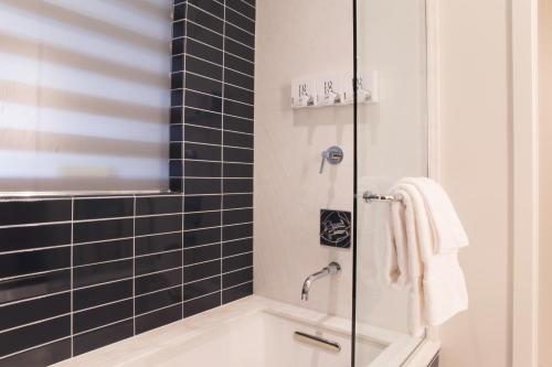 a bathroom with a shower with black tiles at Fairlane Hotel Nashville in Nashville