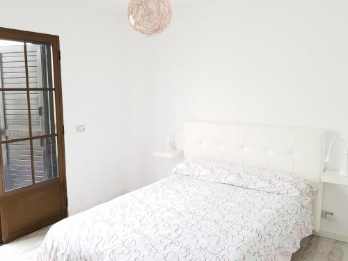 a white bedroom with a bed and a window at Apartamento Playa Agaete in Agaete