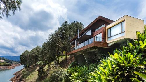 a house on the side of a hill with a river at Luxé Cabañas in Guatapé