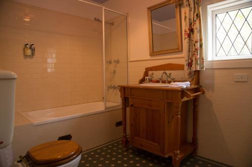 a bathroom with a toilet and a sink and a tub at The Carriages Boutique Hotel and Vineyard in Pokolbin