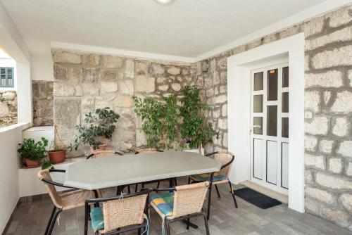 - une table et des chaises dans une pièce dotée d'un mur en pierre dans l'établissement Apartmani Sršen, à Blace