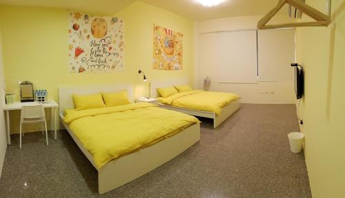 2 camas en una habitación con sábanas amarillas y escritorio en Nice Guanxi, en Guanxi